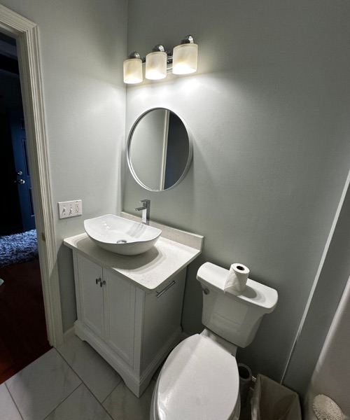 Small bathroom with a vessel sink vanity, round mirror and gray walls