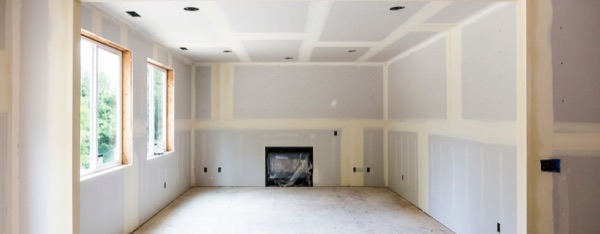 Living room walls finished in new drywall around a fireplace, ready for paint