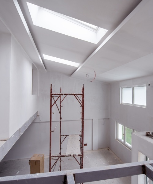 Vaulted ceiling and walls in new drywall, with scaffolding set up for finishing